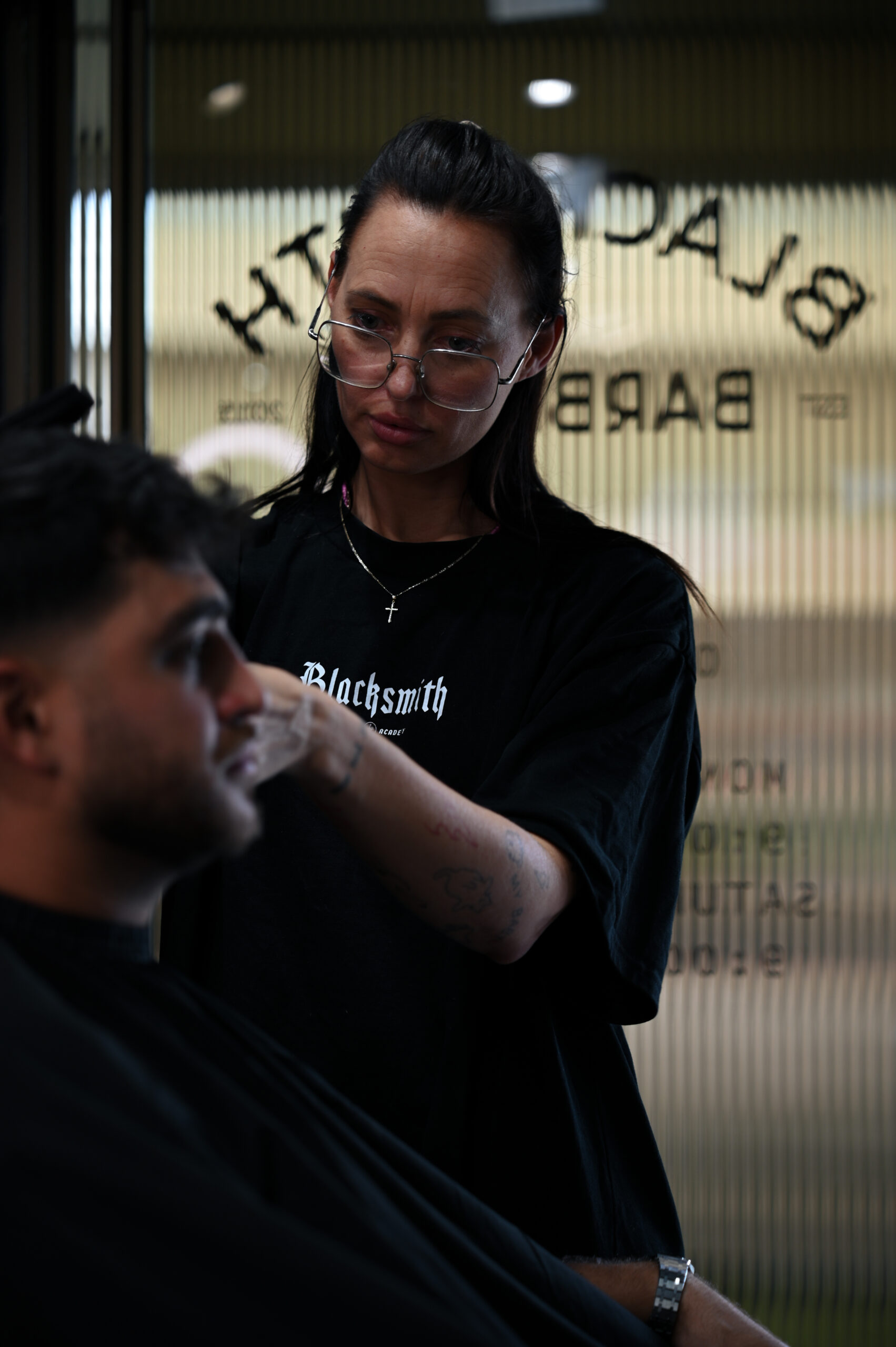A Blacksmith Academy barber working on a client by the shopfront