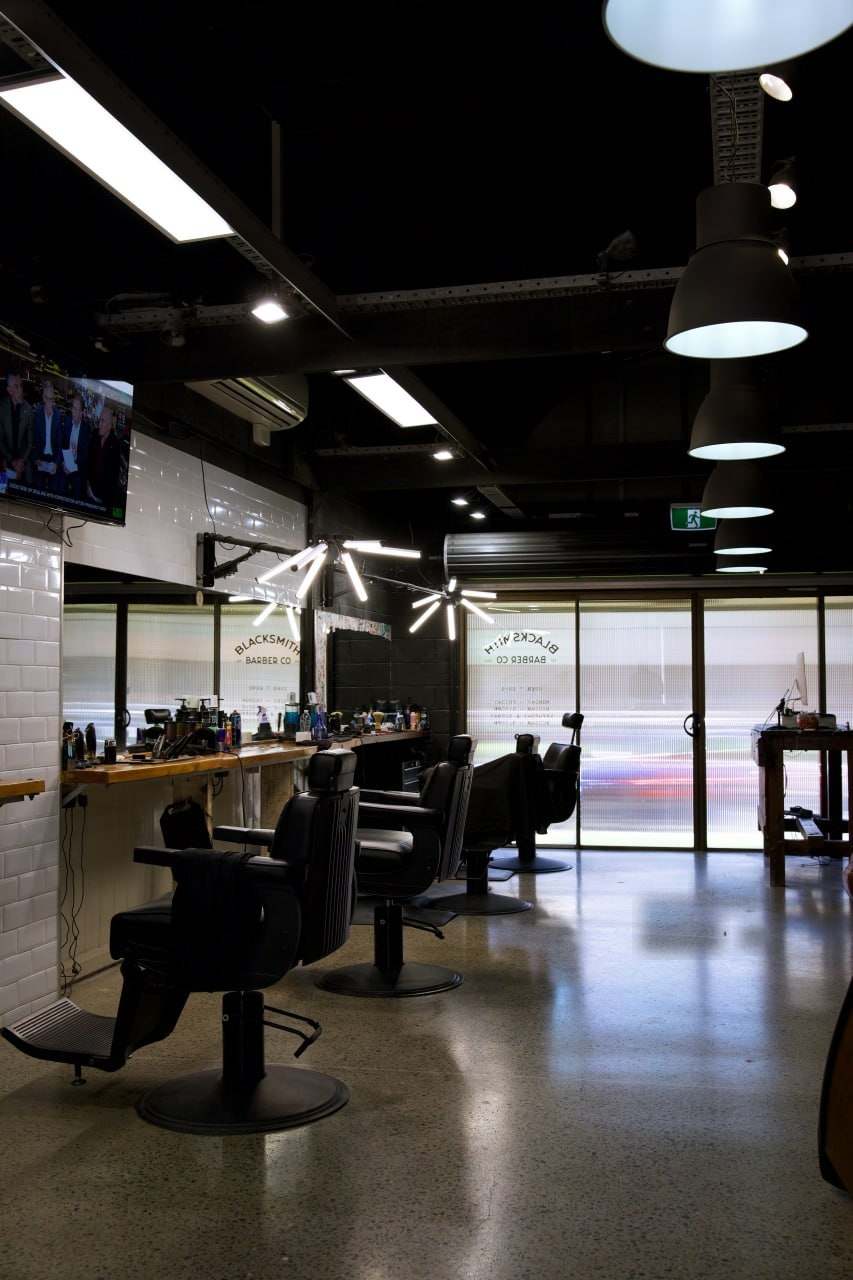 The Blacksmith barbershop floor — barber chairs, frosted Blacksmith Barber Co window and industrial lighting